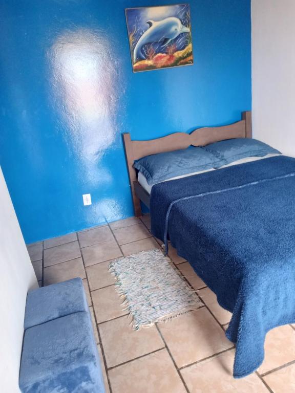 1 dormitorio con cama y pared azul en Pousada paraíso no Mar en Matinhos