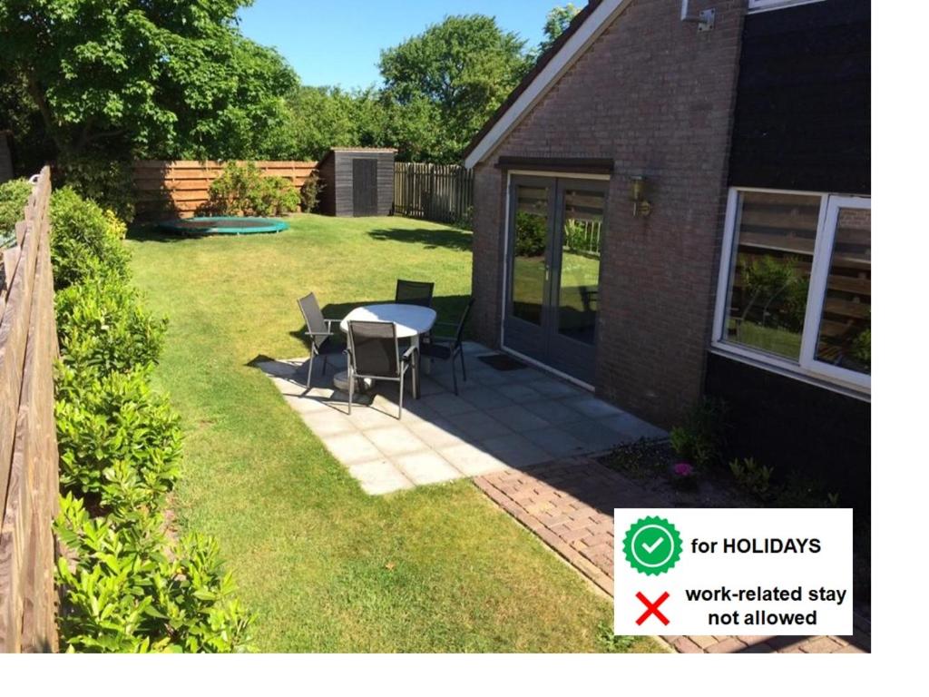 a patio with a table and chairs in a yard at Buitenhuis Egmond in Egmond aan den Hoef