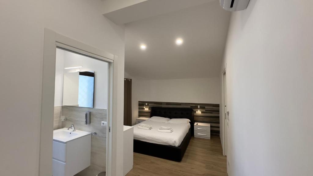 a bedroom with a bed and a sink and a mirror at Le Querce Appartamento Roma in Infernetto