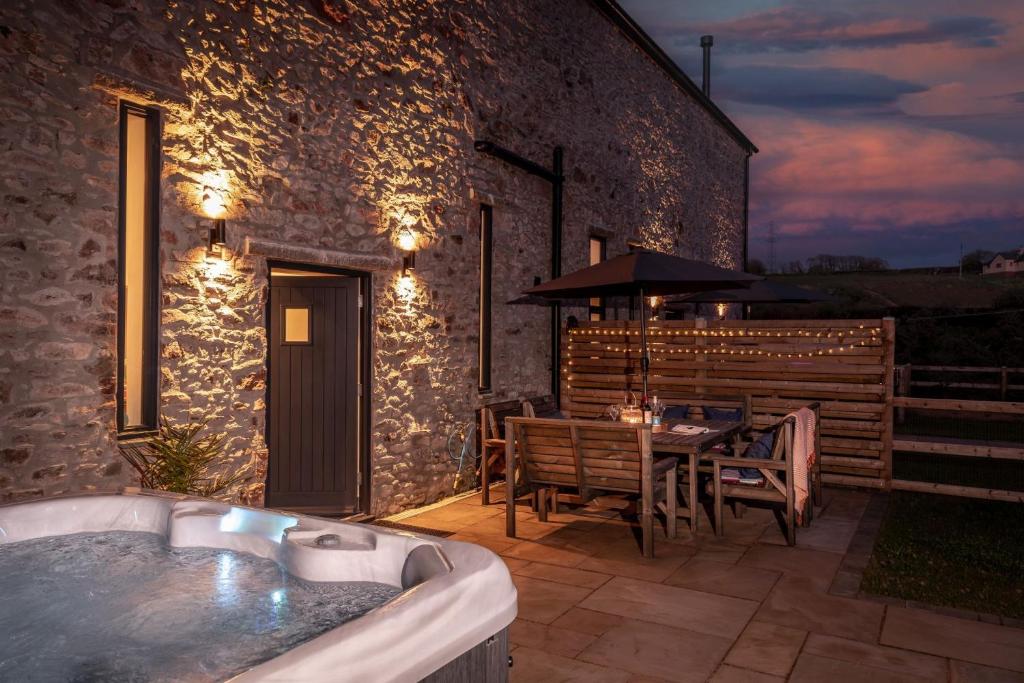 a bath tub sitting next to a patio with a table at The Granary, Higher Yalberton Farm in Paignton