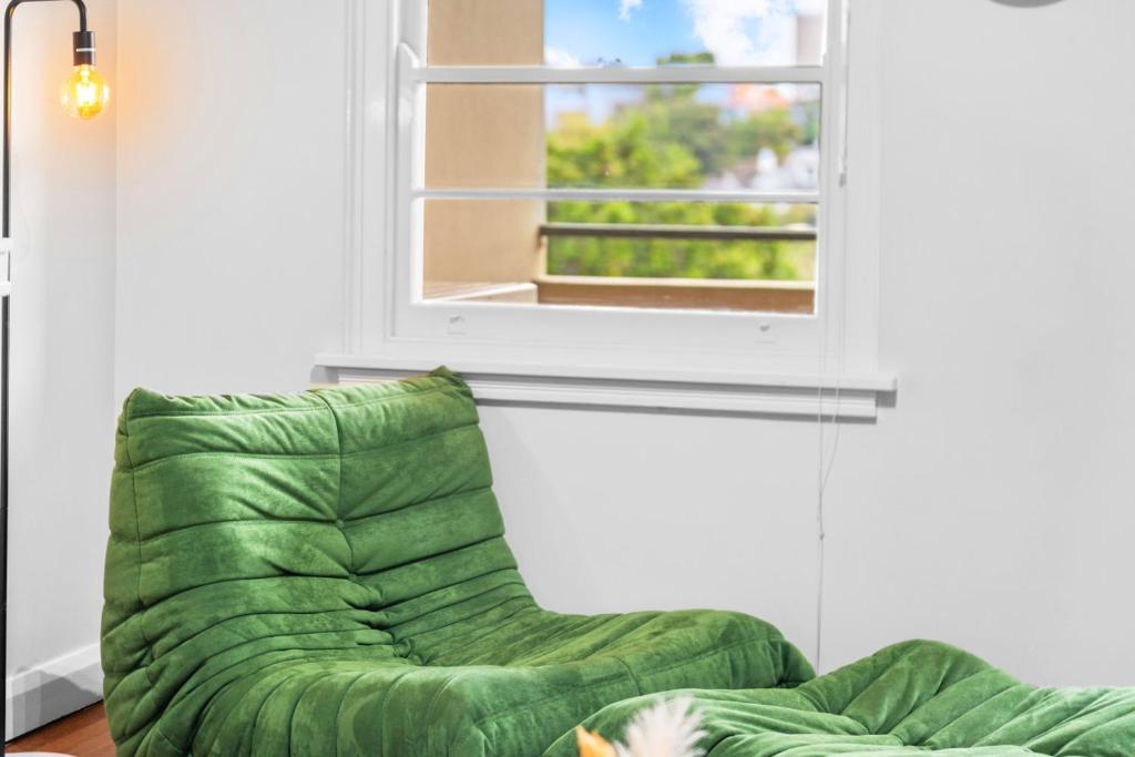 a green couch in a living room with a window at Harbour Bridge View 2BR Resort in Sydney