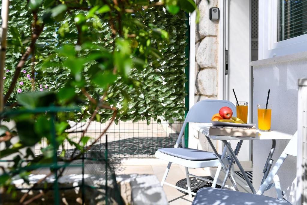 una mesa y una silla en un porche con una fruta. en Val Apartments, en Dubrovnik