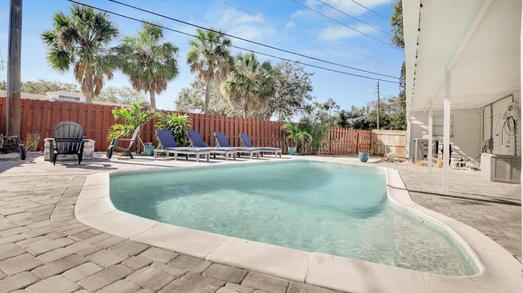 einen Pool in einem Garten mit Stühlen und einem Zaun in der Unterkunft Sarasota home with Outdoor Oasis in Sarasota