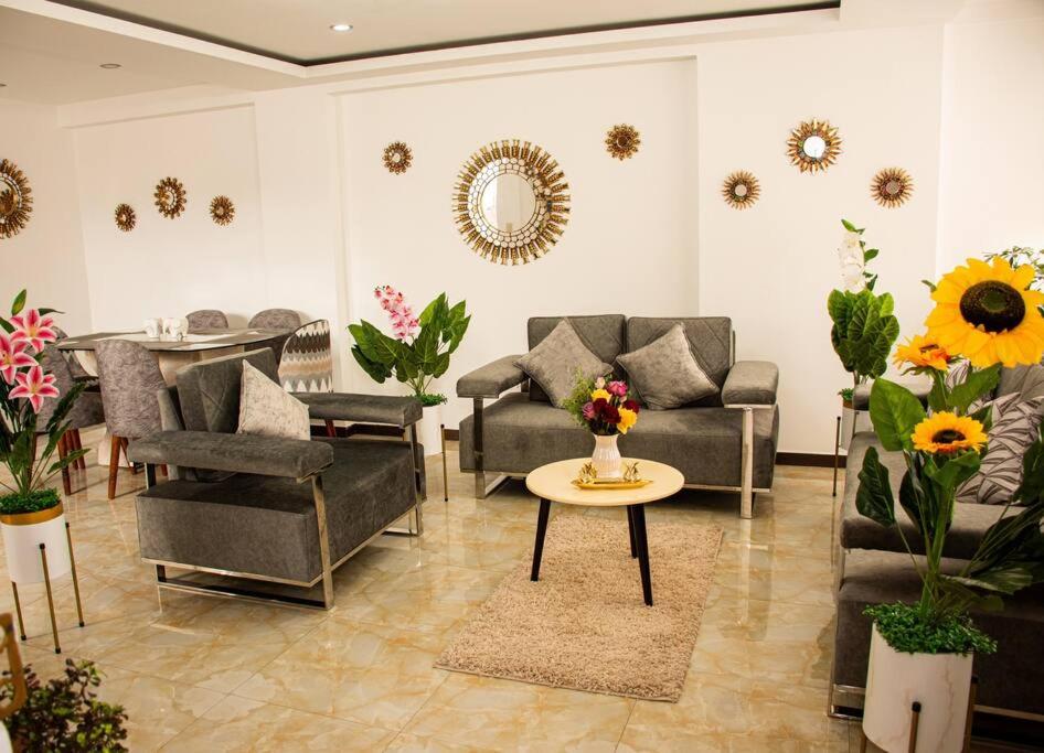 a living room with couches and a table and flowers at Departamento Familiar Alado del aeropuerto in Cusco