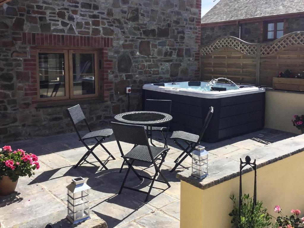 a patio with a table and chairs and a tub at 2 bed in Clovelly 56720 in Woolfardisworthy