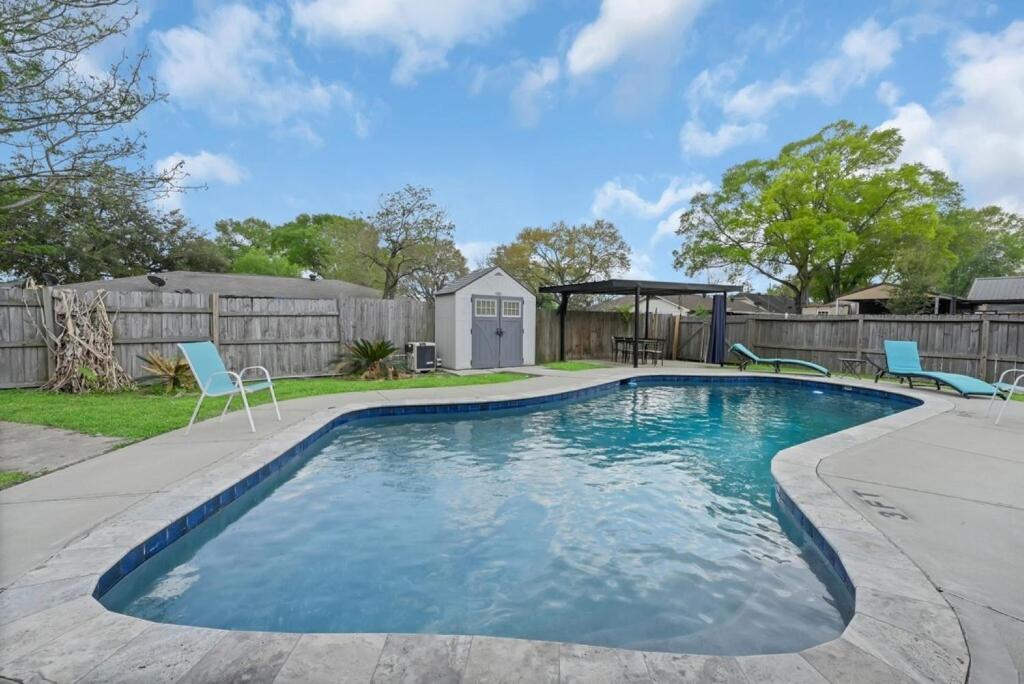a swimming pool with chairs and a gazebo at Pool/ Outdoor kitchen/Pool table in Houston