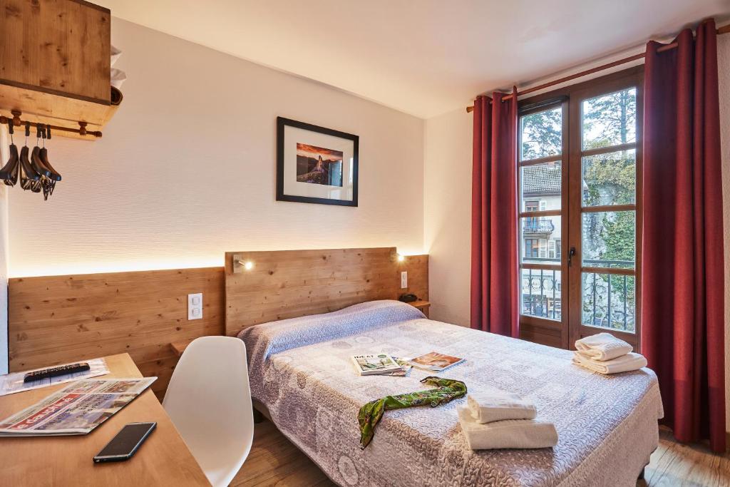 a bedroom with a bed and a desk and a table at Cit'H&ocirc;tel Le National in Cluses
