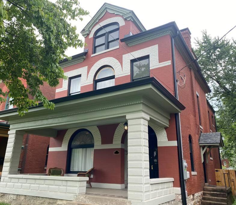 uma casa vermelha e branca com um cão sentado no alpendre em DERBY LUXE 3-story Historic 6 min from Churchill em Louisville