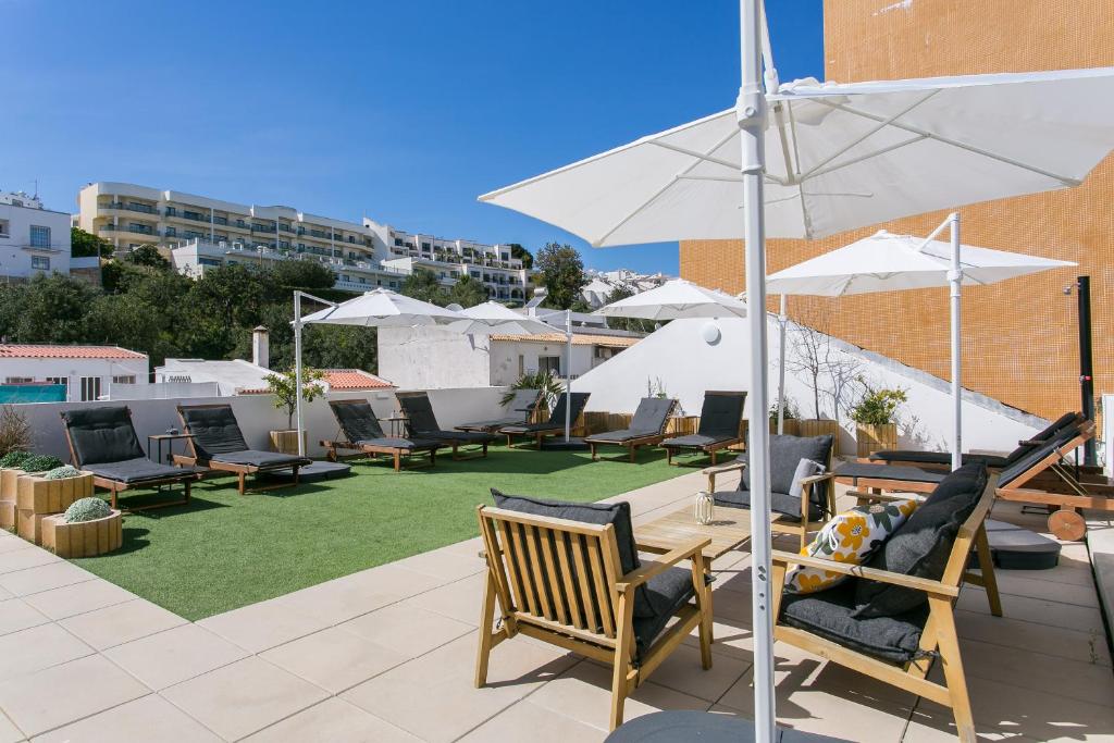a patio with chairs and a table and an umbrella at Golden Stay - B&B Experience in Albufeira