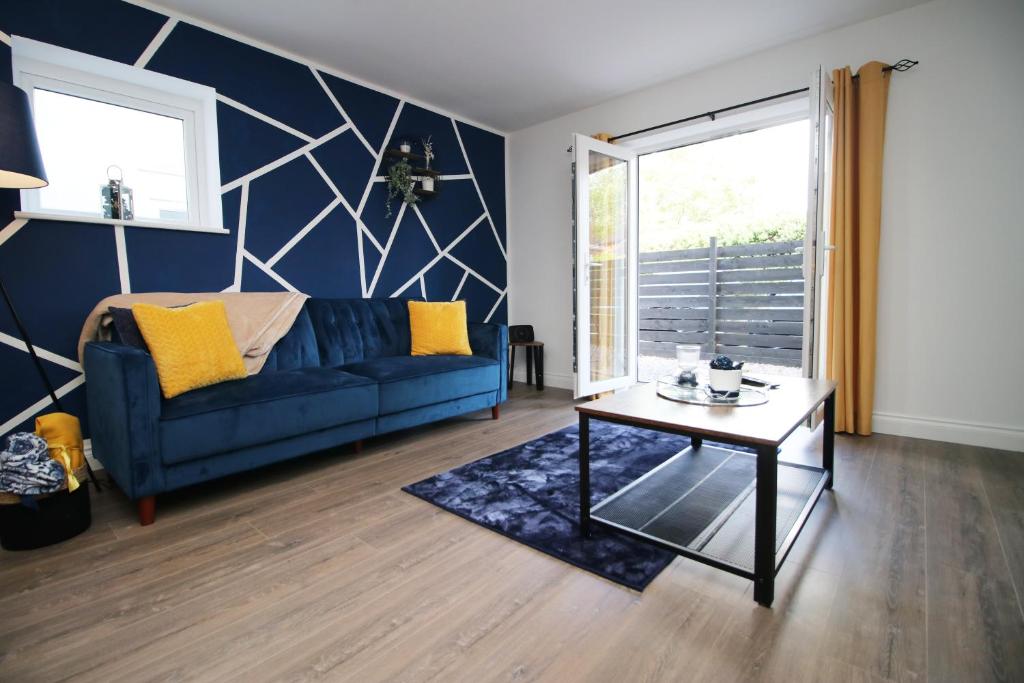 a living room with a blue couch and a table at Casa di pietra - Cardiff City centre apartment with patio, Free private parking in Cardiff