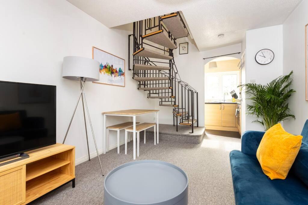 uma sala de estar com um sofá azul e uma escada em espiral em Beautiful House by Station with Private Parking em Cambridge