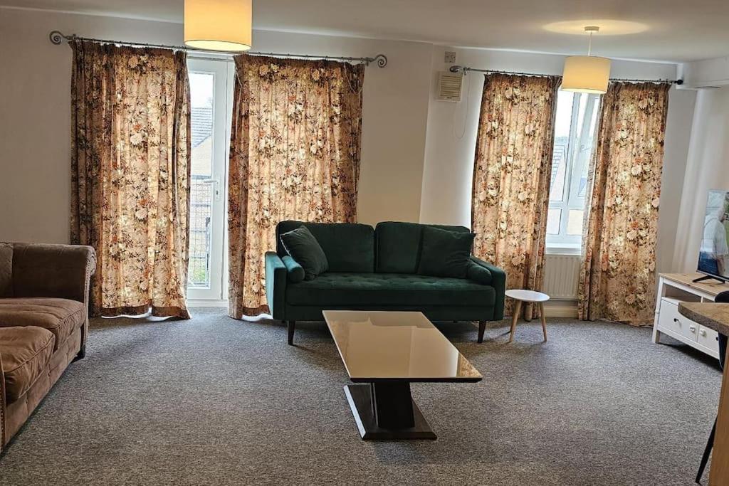 een woonkamer met een groene bank en gordijnen bij A well looked after 2 bedroom flat in Sheffield