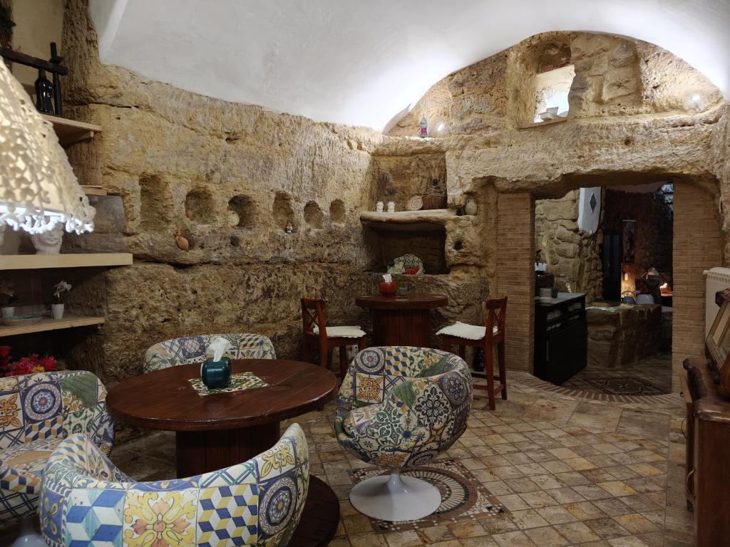 Pokój ze stołem i krzesłami oraz kamienną ścianą w obiekcie Proserpina w mieście Enna