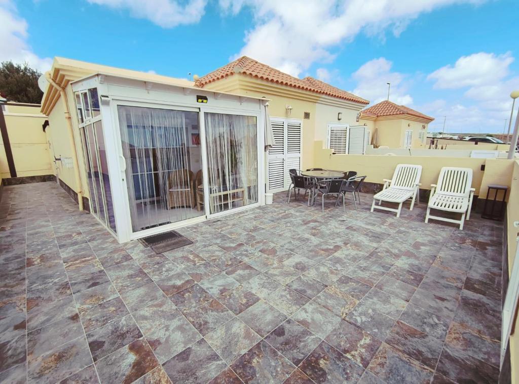 a patio with a table and chairs in front of a house at Brisa Marina - Vista Golf 2 - WiFi - swimming pool in Caleta De Fuste
