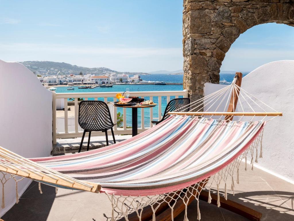 a hammock on a balcony with a view of the ocean at Yalos Hotel Sunset view Mykonos town private rooms in Mýkonos City