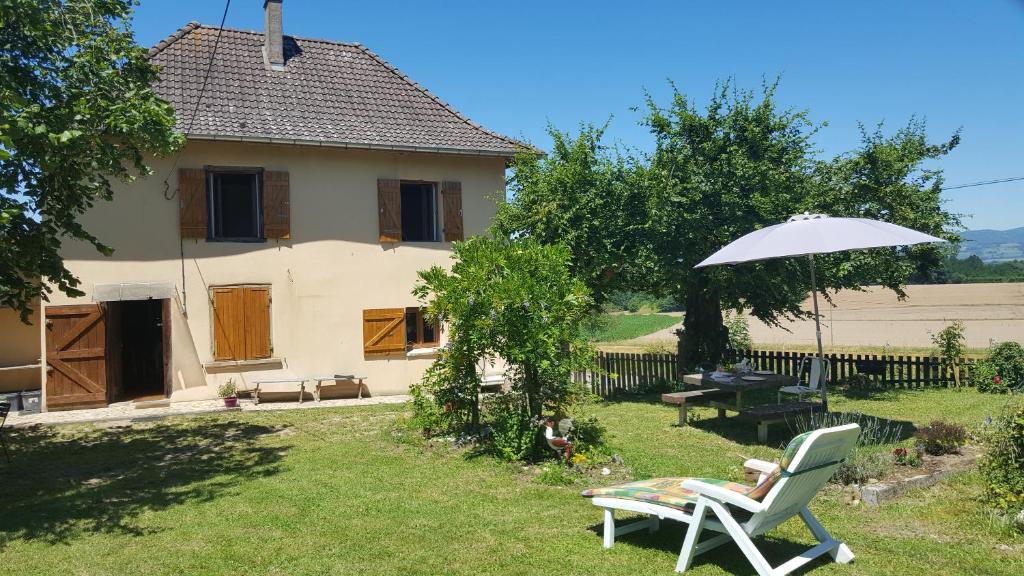 une cour avec une chaise et un parasol ainsi qu'une maison dans l'établissement Gite 8p Chartreuse Vercors, à Saint-Jean-dÊ¼Avelanne