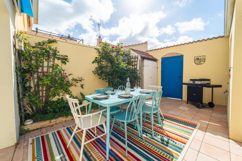 un patio con una mesa azul y sillas en Confortable maison joliment décorée, en Les Sables-dʼOlonne