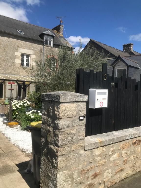einen Briefkasten an einer Steinmauer neben einem Zaun in der Unterkunft Charmante maisonnette proximité cité médiévale et bords de Rance in Dinan