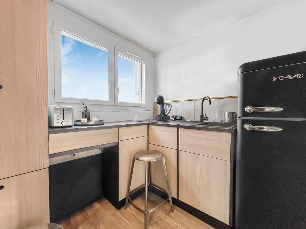 a kitchen with a black refrigerator and a sink at Le coin cosy d'Anglet in Anglet