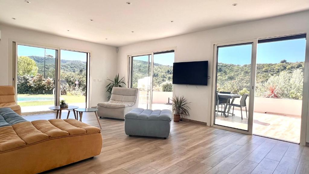 un salon avec un canapé, des chaises et une télévision dans l'établissement Villa contemporaine bord de mer Saint Aygulf, à Fréjus