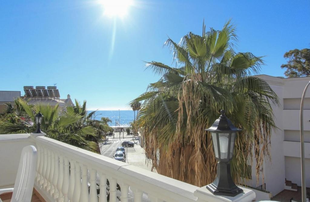 a balcony with a view of the beach and palm trees at Burriana Casa Playa in Nerja
