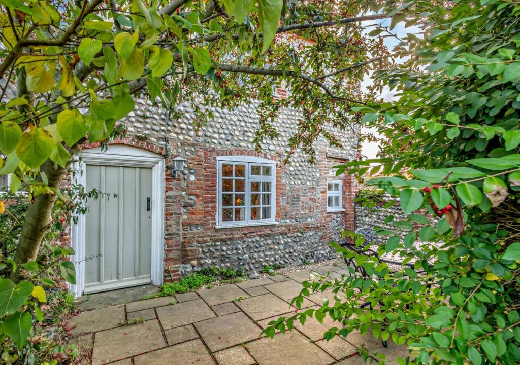 a brick house with a white door and window at Bakers Cottage - Sidestrand in Sidestrand