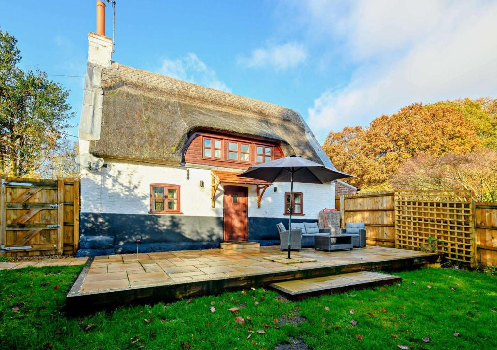 Panxworth的住宿－Holly Cottage，小屋设有遮阳伞和木甲板