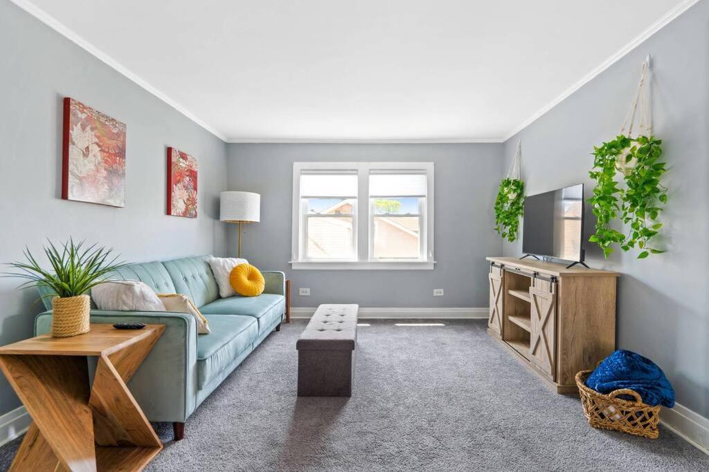 a living room with a blue couch and a tv at Norwood Park/Edison Park! Workstation & In-unit Laundry! 2nd Floor Apt in Chicago