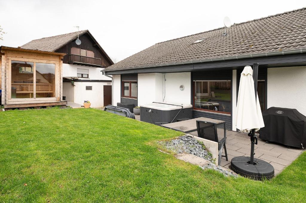 a patio with a white umbrella and a house at Eifel-resort in Waxweiler
