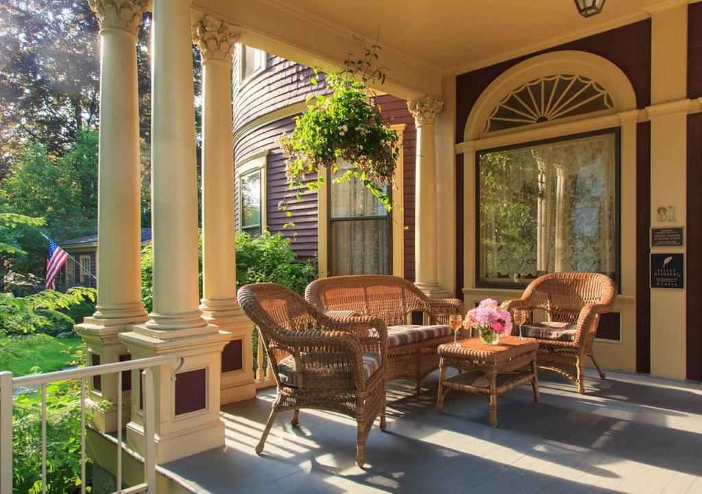 a porch with wicker chairs and a table with flowers on it at Berry Manor Inn in Rockland