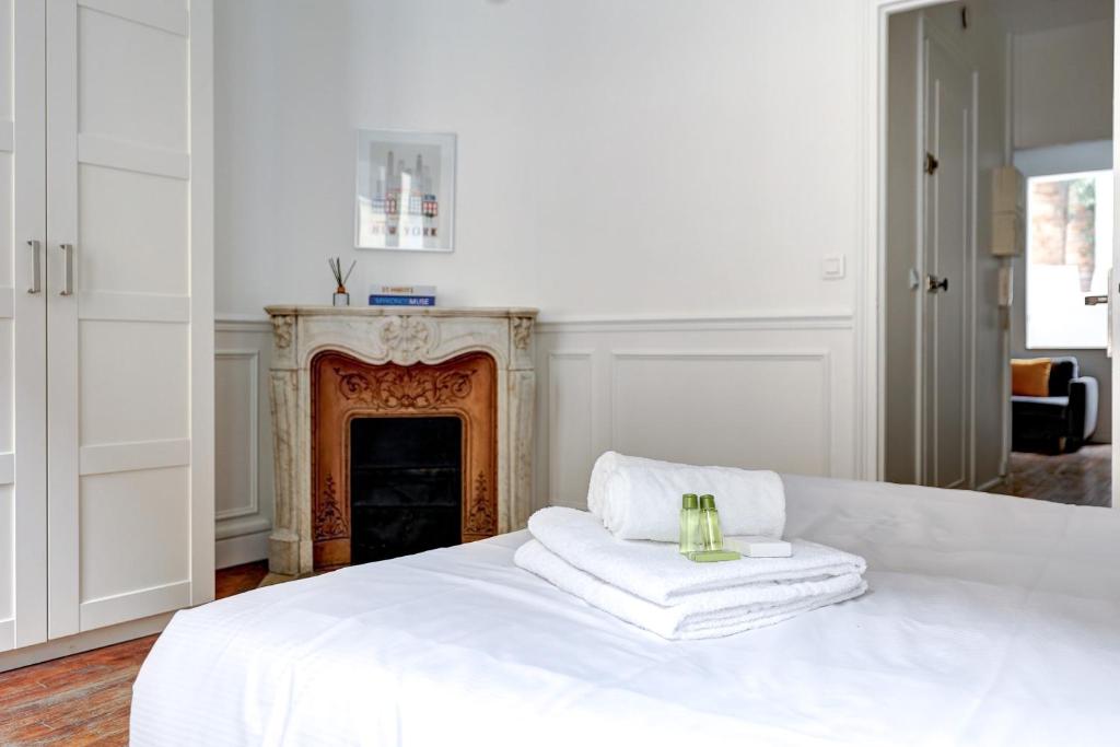 1 dormitorio blanco con chimenea y toallas blancas en la cama en 101- Beautiful apartment near champs elysees en París