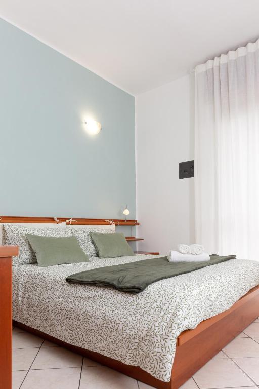 a white bedroom with a bed with green pillows at ArtStay Exclusive Apt Linate, Parking, Terrace AC in Pioltello