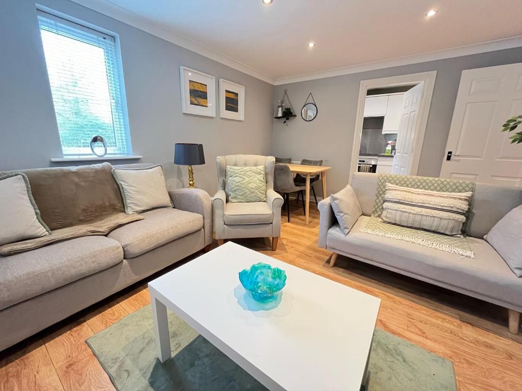 a living room with two couches and a table at Contractors welcome GF flat sleeps 4 with parking by Eagle Owl Property in Crawley