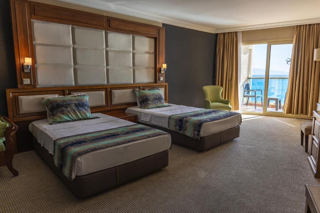 クシャダスにあるSCALA NUOVA BEACH HOTELのベッド2台とバルコニーが備わるホテルルームです。
