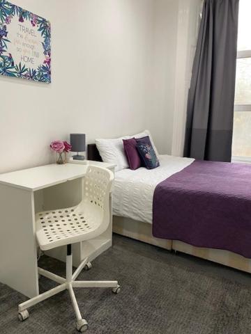 a bedroom with a desk and a bed with purple sheets at LORD MERIT GUEST HOUSE KING'S CROSS GRAYS INN ROAD in London