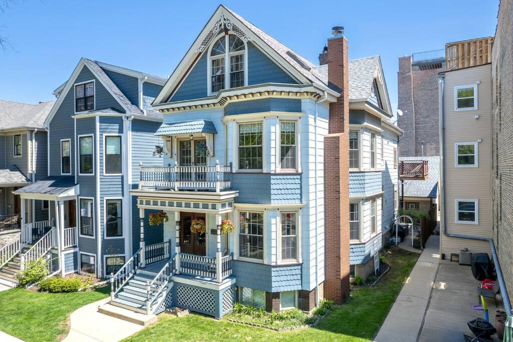 a blue house with a porch on a street at NEW! XL North Center Apt - 2 Car Garage and EV Charger! Patios! in Chicago