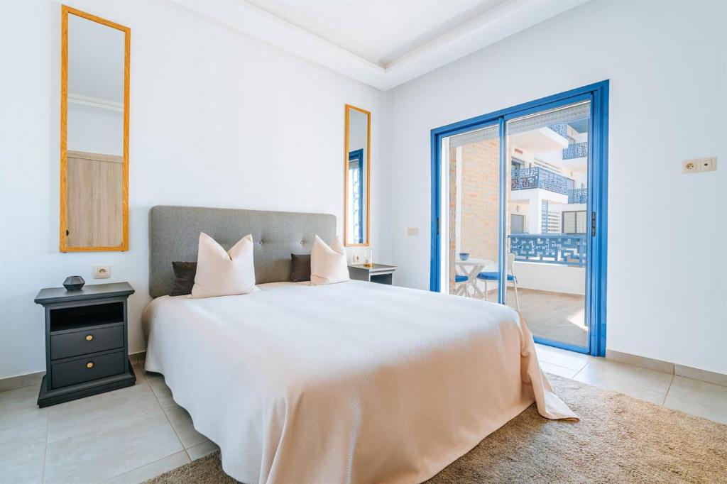 een slaapkamer met een groot wit bed en een balkon bij Residence Costa-Mar in Martil