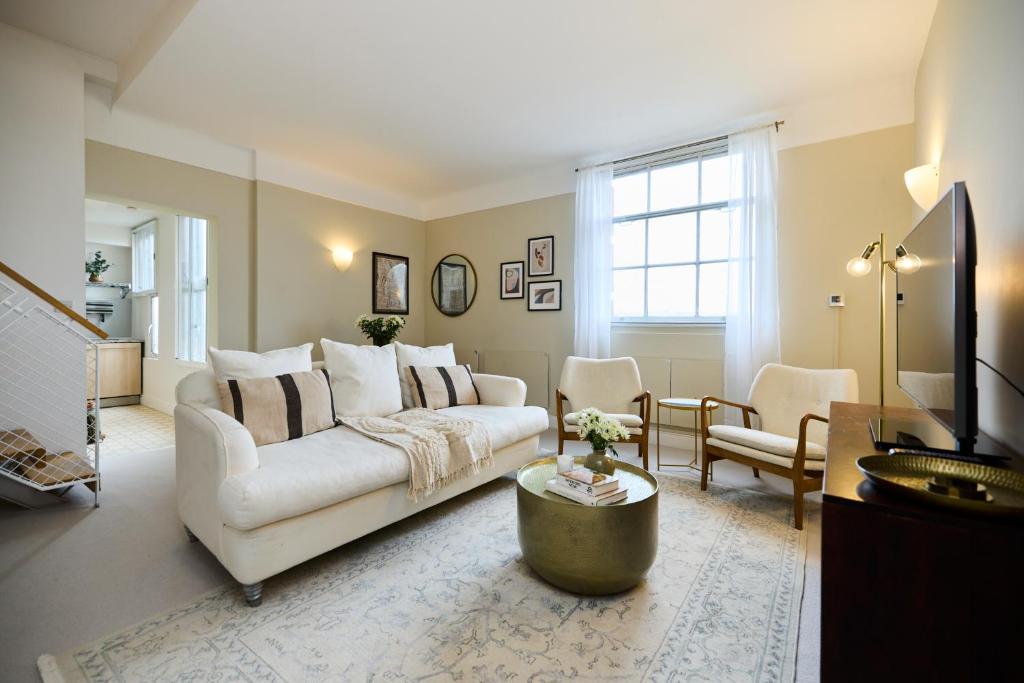ein Wohnzimmer mit einem weißen Sofa und einem Tisch in der Unterkunft The Manor Gardens Retreat - Captivating 1BDR Flat with Terrace in London