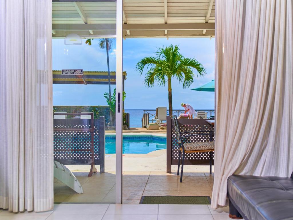 a room with a view of the pool and the ocean at Tropical Sunset Beach Apartment Hotel in Saint James