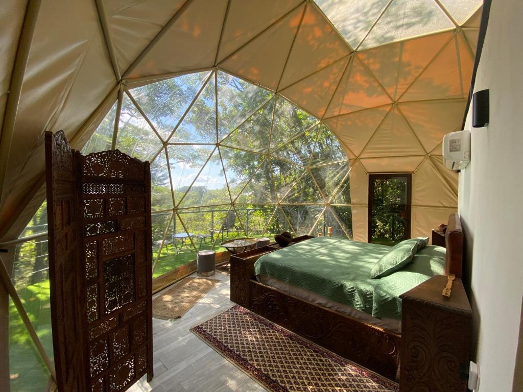 モンテベルデ・コスタリカにあるWay To Heaven Glampingのテント内のベッド1台、大きな窓が備わる客室です。