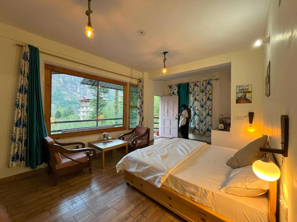 a bedroom with a bed and a large window at Rishi Villa in Manāli
