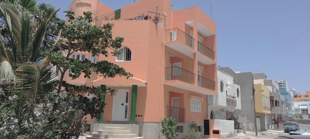 een roze gebouw op een straat met een palmboom bij Laginha Beach Guest House in Mindelo