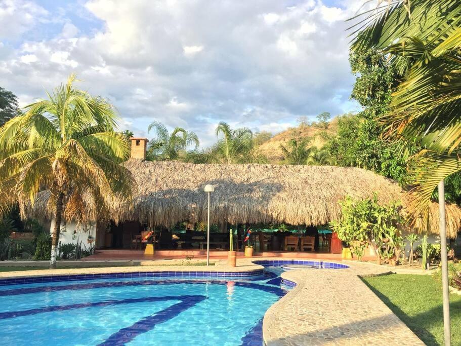 ein Resort mit einem Pool und einem Strohdach in der Unterkunft Finca el Costurero, SantaFe de Antioquia in Medellín
