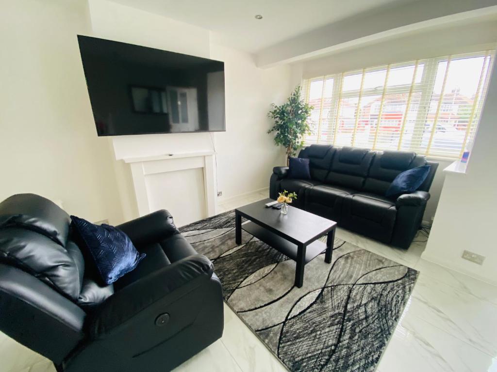 sala de estar con sofá negro y mesa en Inviting 4-Bed House in Leeds, en New Malden