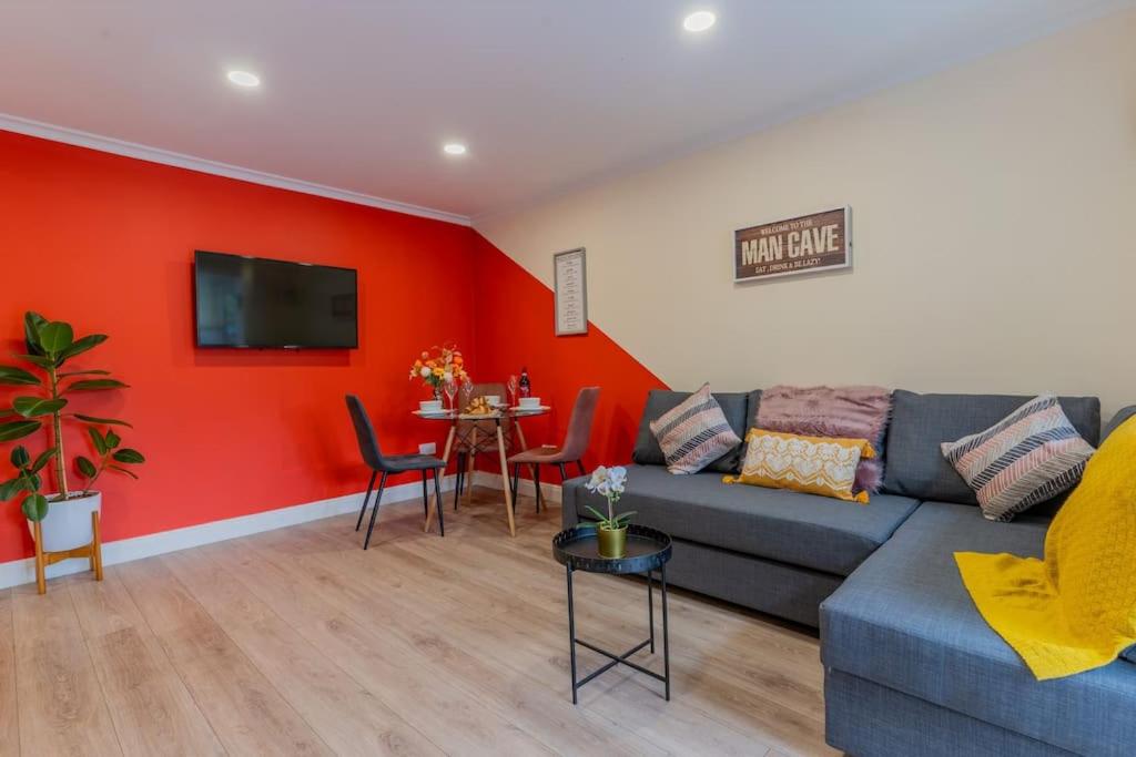 a living room with a blue couch and a red wall at Hayes Home - Easy links to LHR and London in Northolt