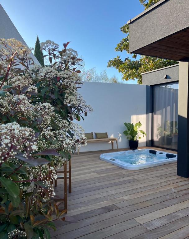 un jardin avec un bain à remous sur une terrasse fleurie dans l'établissement Lodge Valbelle, maison indépendante avec jacuzzi, à Tourves