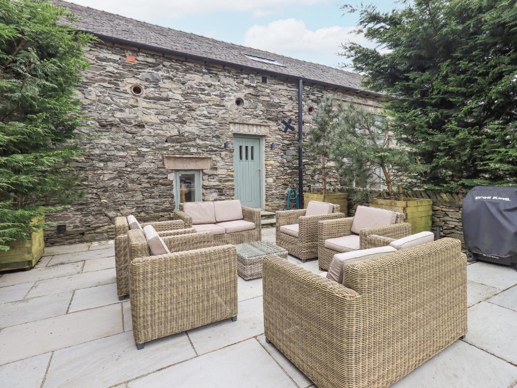 eine Gruppe Korbstühle und Tische auf einer Terrasse in der Unterkunft Yew Cottage in Backbarrow