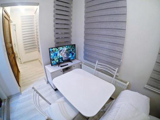 a living room with a white table and a television at Taksim Cihangir otel in Istanbul