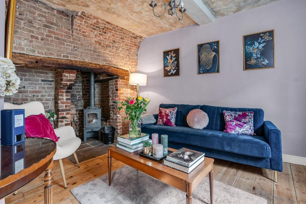 a living room with a blue couch and a brick wall at The Blue Anchor House - close to London in Hertford