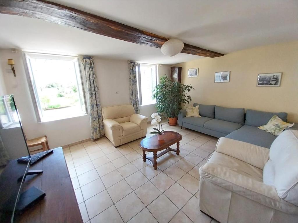 a living room with a couch and a table at Entre forêts et prairies in Le Cercueil